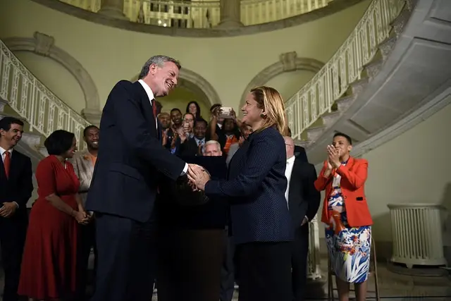 Mayor de Blasio and Speaker Melissa Mark-Viverito shaking hands on the FY 2018 Budget in June. When this photo was taken, no agreement had been reached on immigrant defense funding.